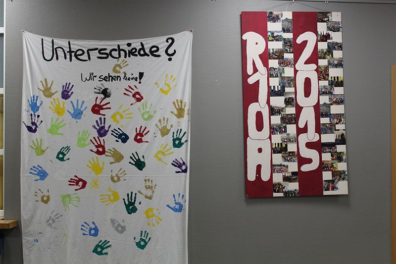 Weißes Banner mit bunten Handabdrücken und deutschem Text, daneben eine Fotocollage mit der Aufschrift „R 2015“ in Weiß.