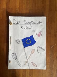 Handgefertigter Kochbuchumschlag: „Das europäische Kochbuch“ mit EU-Flagge, Küchenutensilien und Zeichnungen zum Thema Kochen.