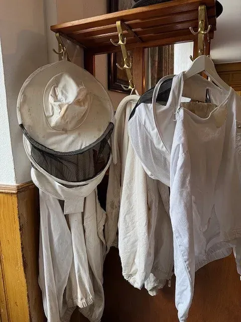 Imkeranzüge und -hüte hängen an einer hölzernen Garderobe.
