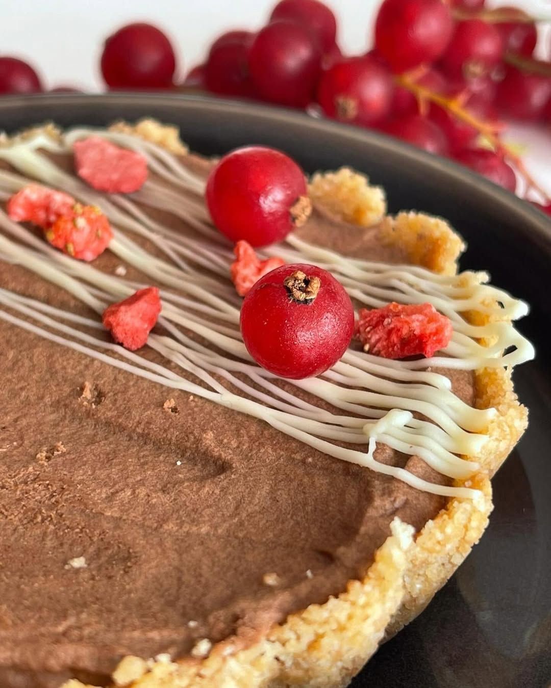 Un plato negro cubierto con patatas y salsa sobre una mesa de madera.