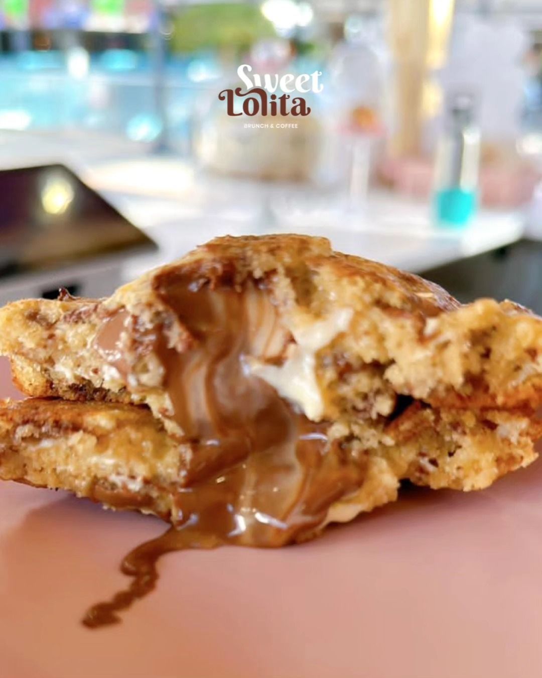 Pastel relleno bañado en chocolate sobre un plato rosa, con un fondo de café difuminado.