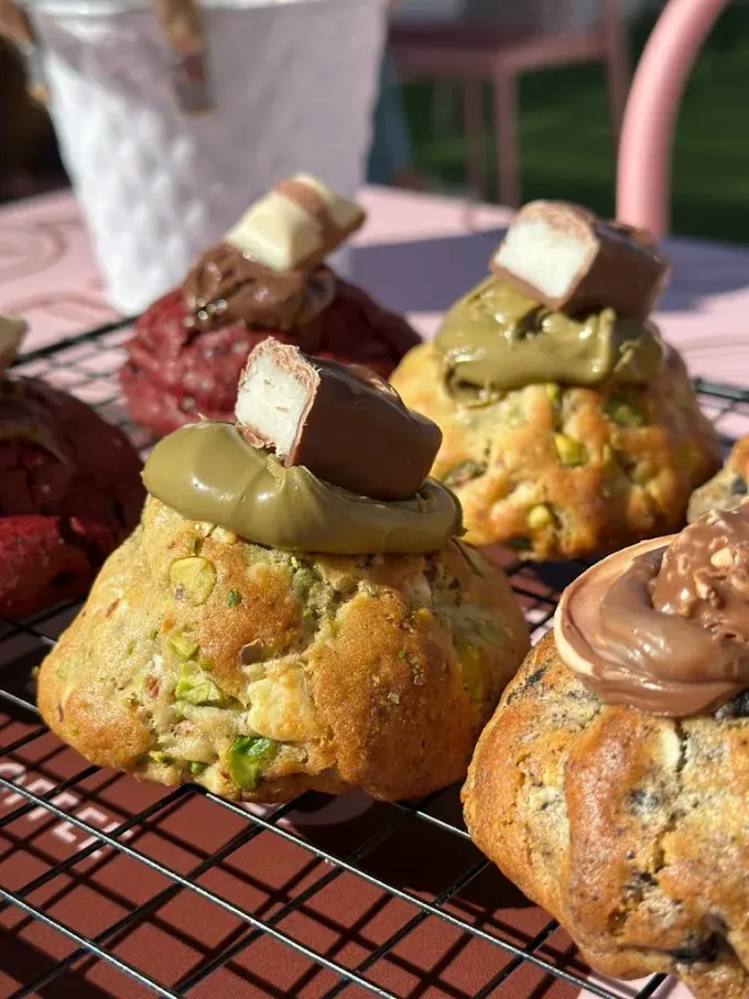 Pasteles cubiertos de chocolate y crema sobre una rejilla metálica a la luz del día.