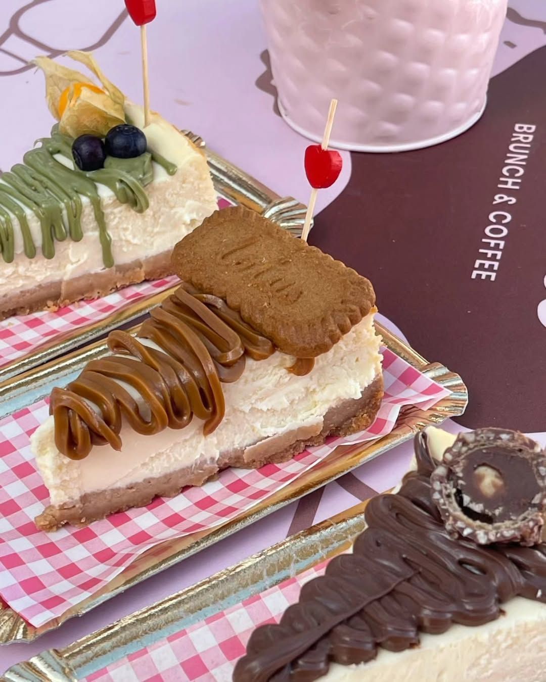 Postres en una bandeja: rebanadas de pastel cubiertas con chocolate, caramelo y fruta junto a una taza de café.