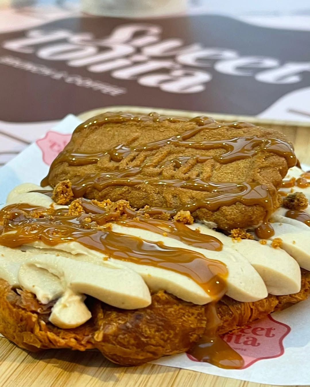 Pasteles apilados cubiertos con crema blanca y salsa de caramelo, con un trozo de chocolate encima.