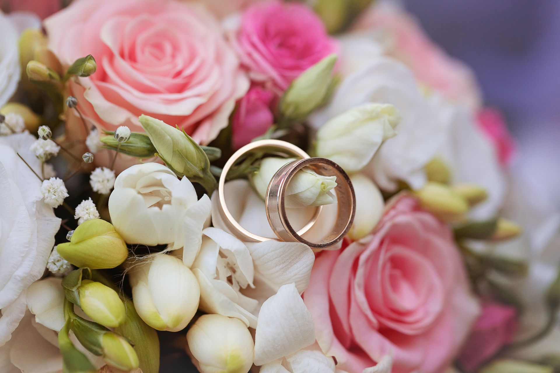 Auf einem Blumenstrauß liegen zwei Eheringe.