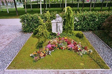 ein Grab mit Blumen und einer Statue in der Mitte