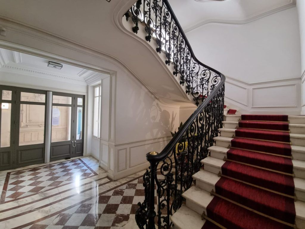 Escaliers en pierre avec tapis rouge et rampe en fer forgé