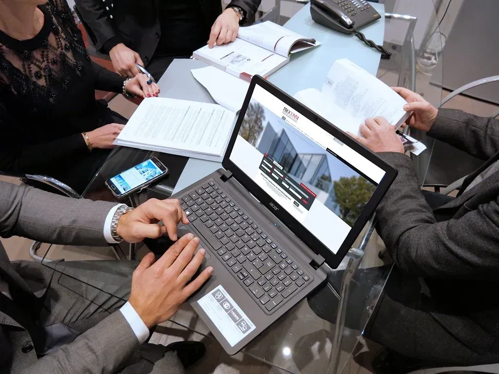 Quatre personnes en costume travaillant sur une table en verre