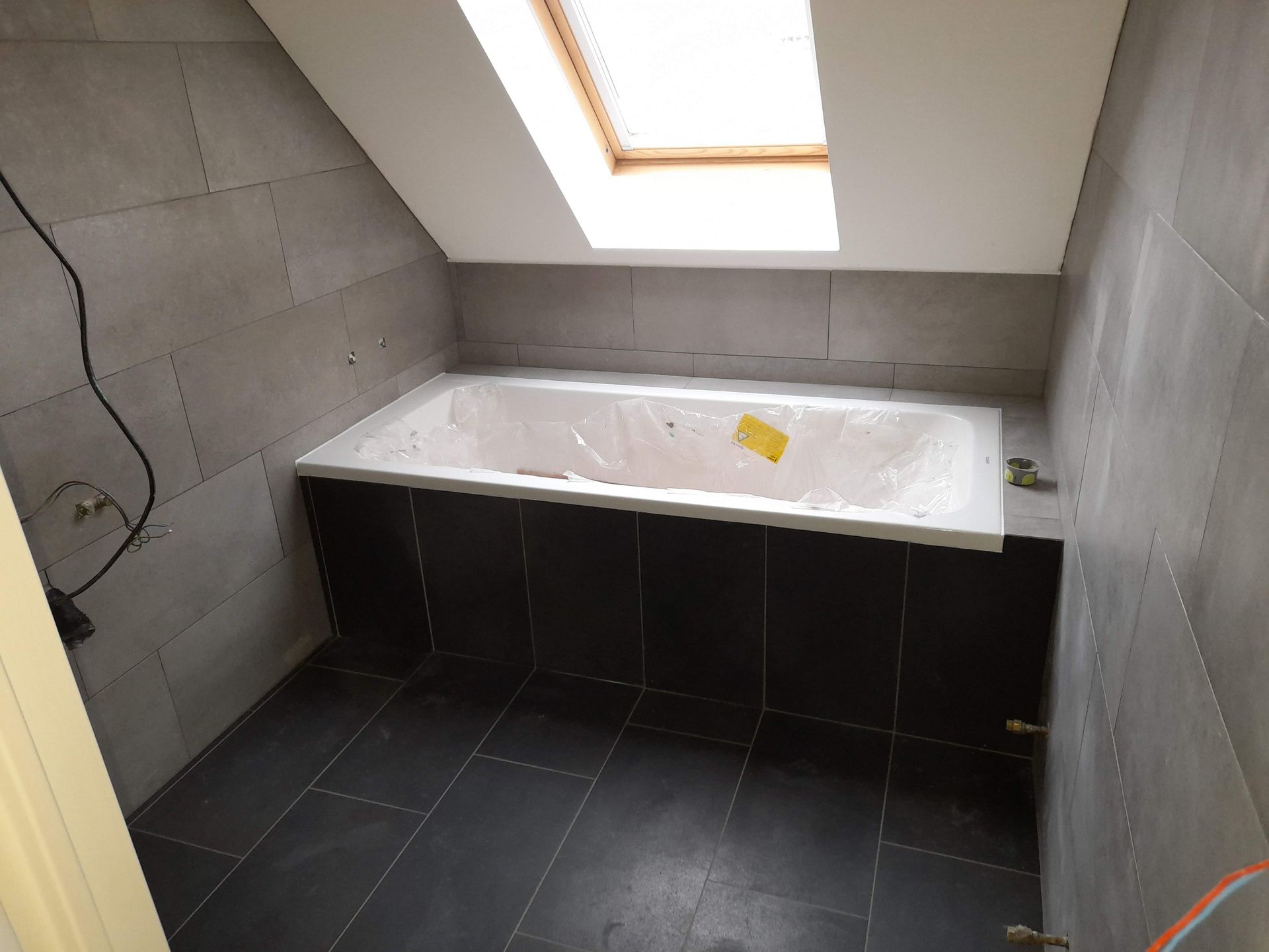 Une baignoire avec carrelage noir et gris