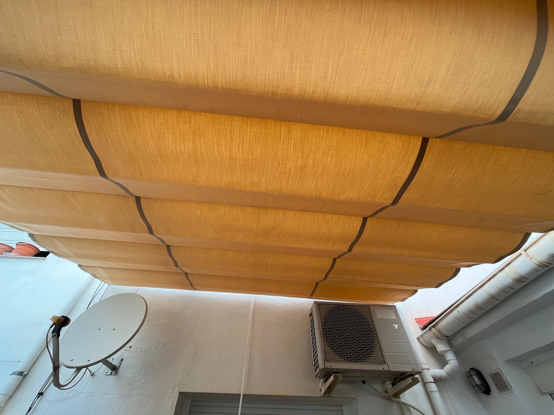 Una antena parabólica está montada en el lateral de un edificio.