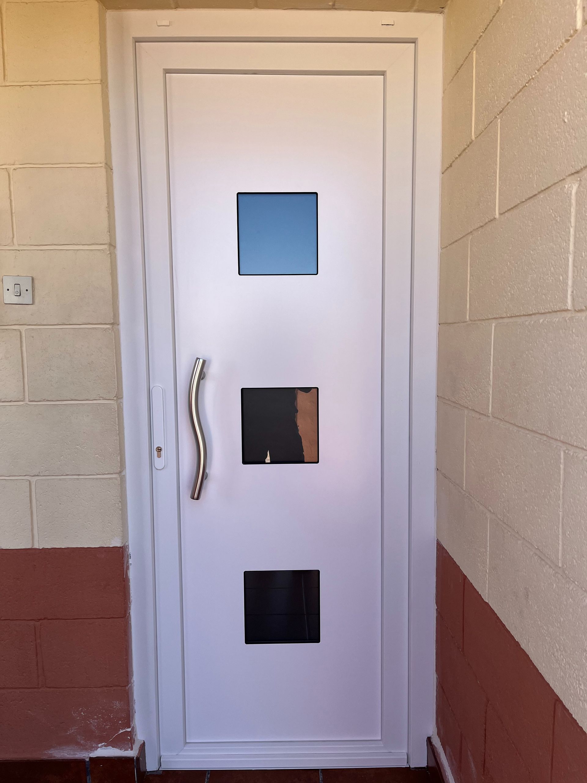 Una puerta blanca con ventanas cuadradas y un tirador.