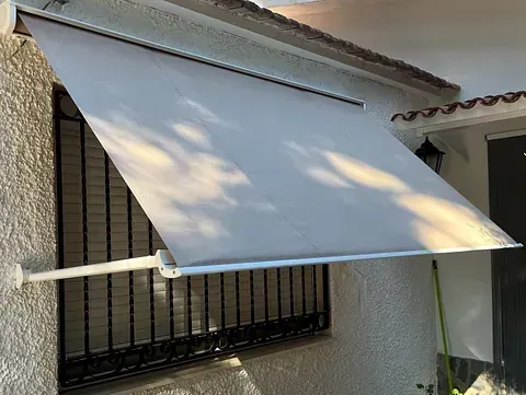 Un toldo blanco cuelga sobre una ventana al costado de un edificio.