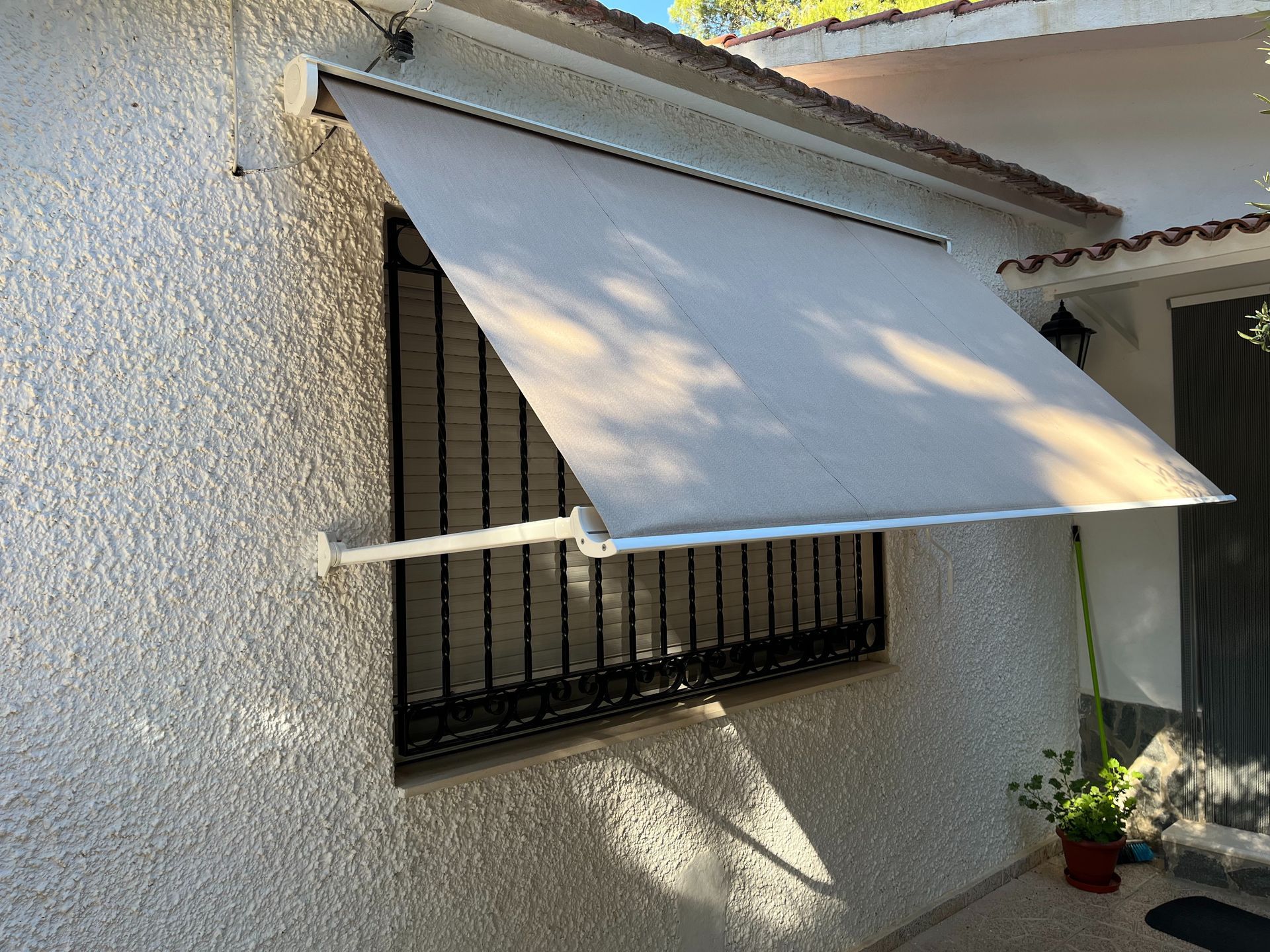 Un toldo blanco cuelga sobre una ventana al costado de una casa.