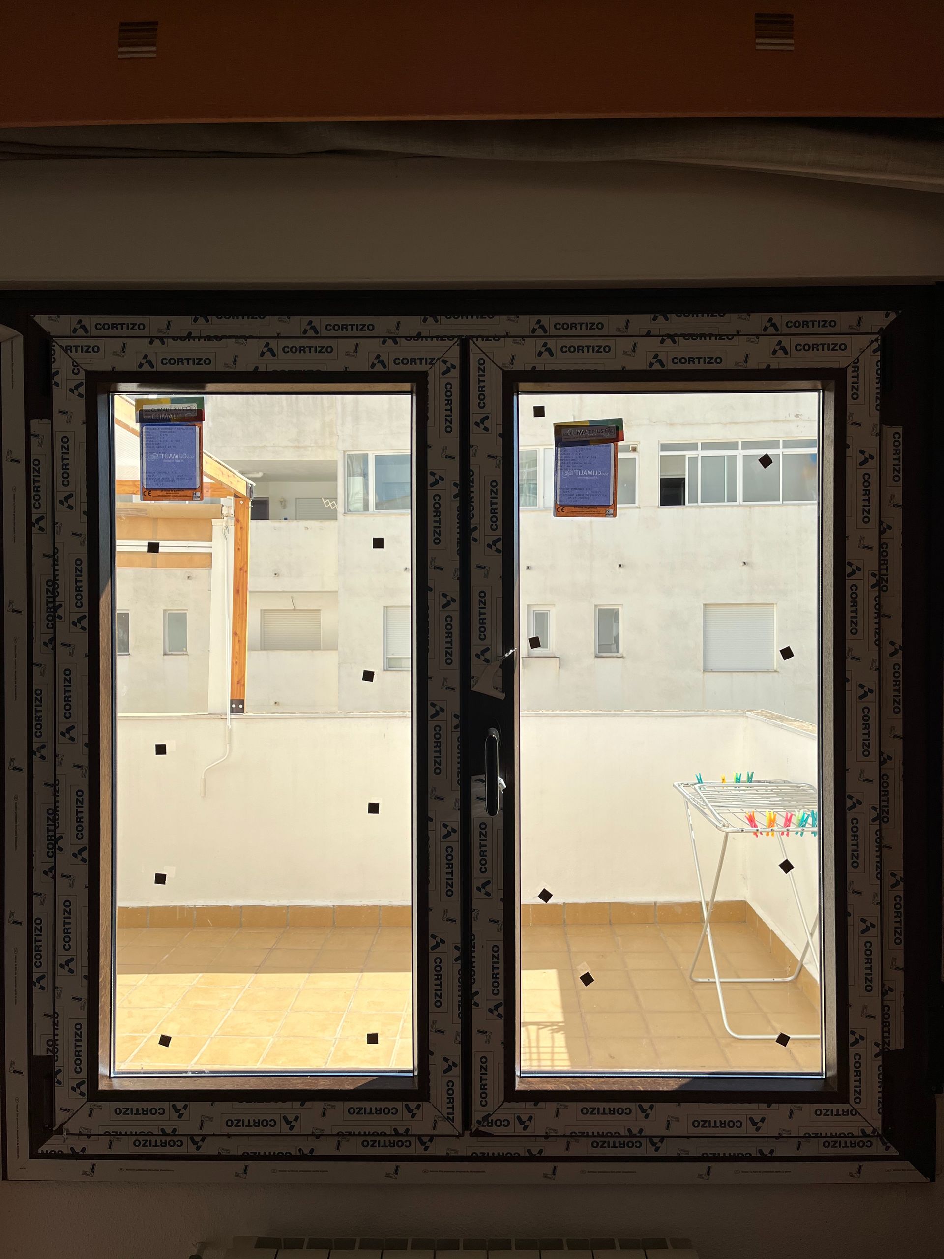 Una ventana con vista a un balcón y edificios.