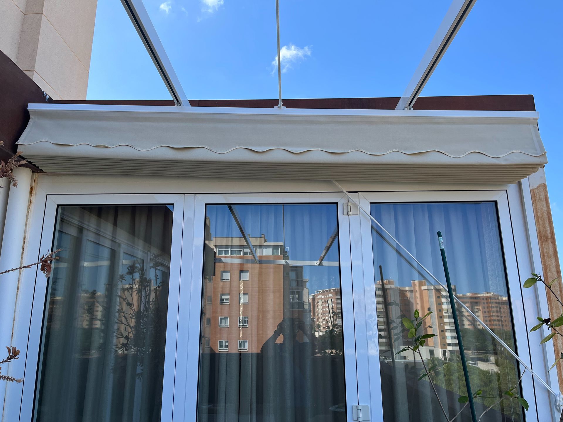 Una ventana con un dosel encima y un reflejo de una ciudad en la ventana.