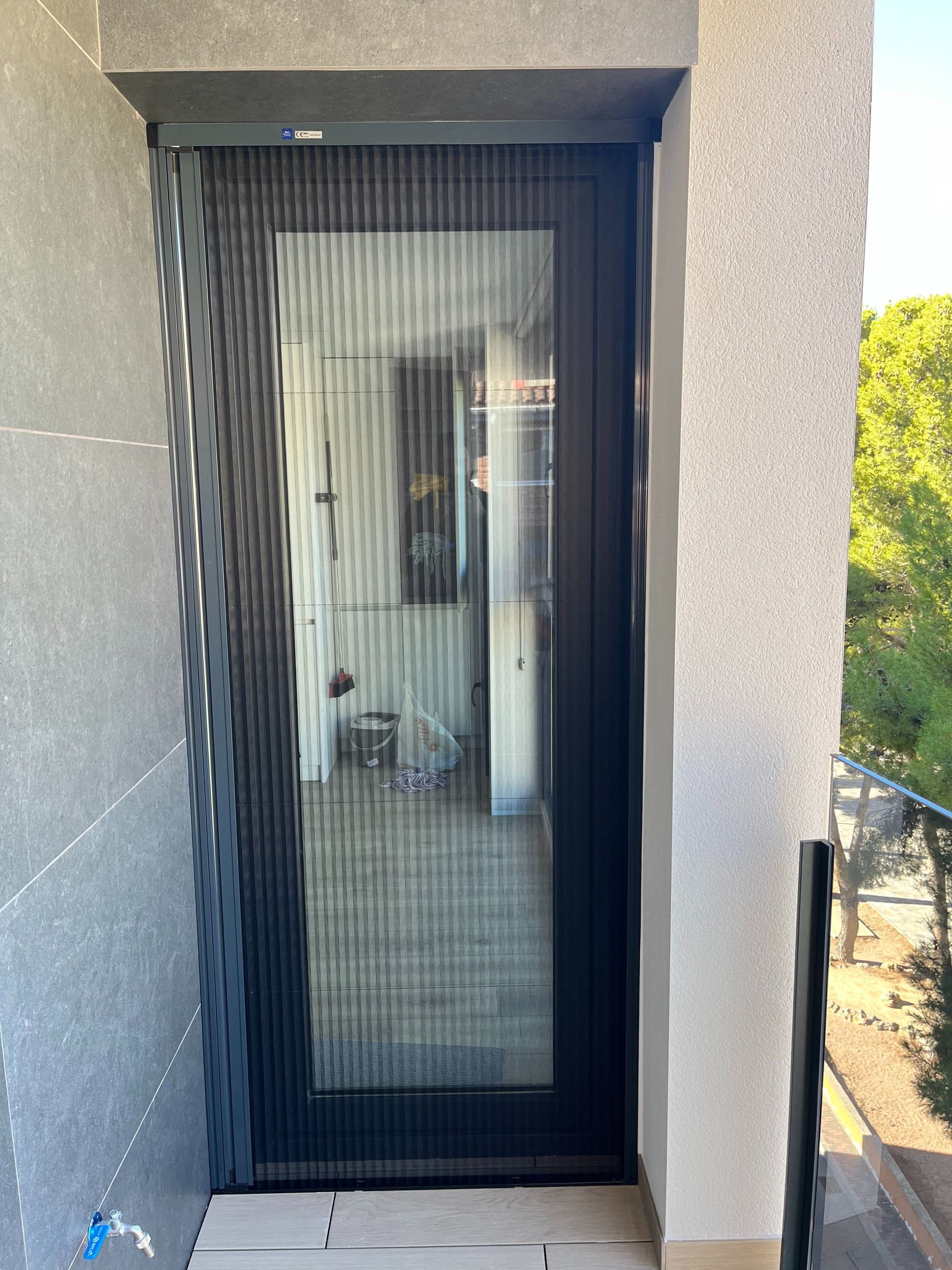 Una puerta negra con un mosquitero está sentada en un balcón.