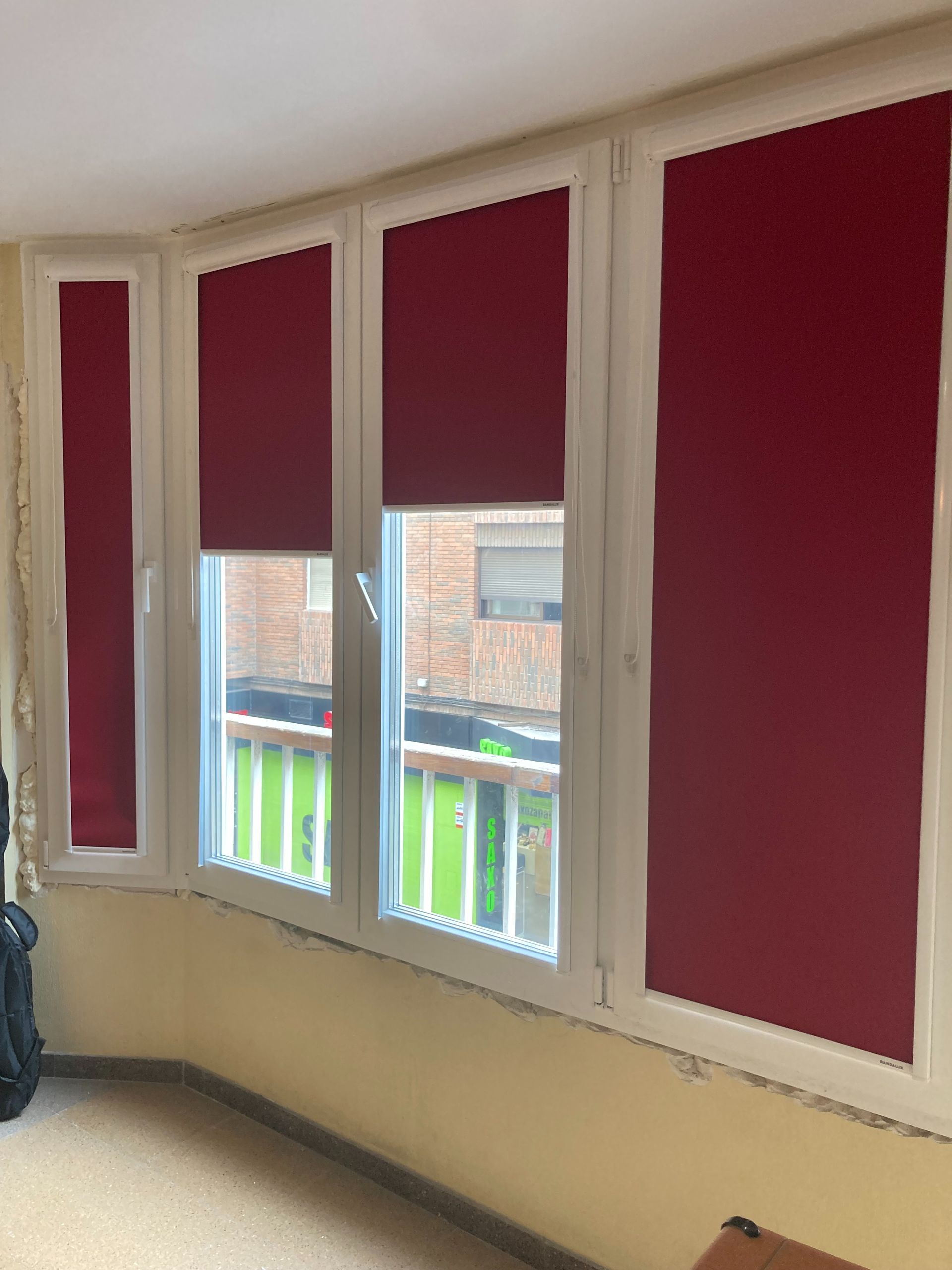 Una habitación con muchas ventanas y persianas rojas.