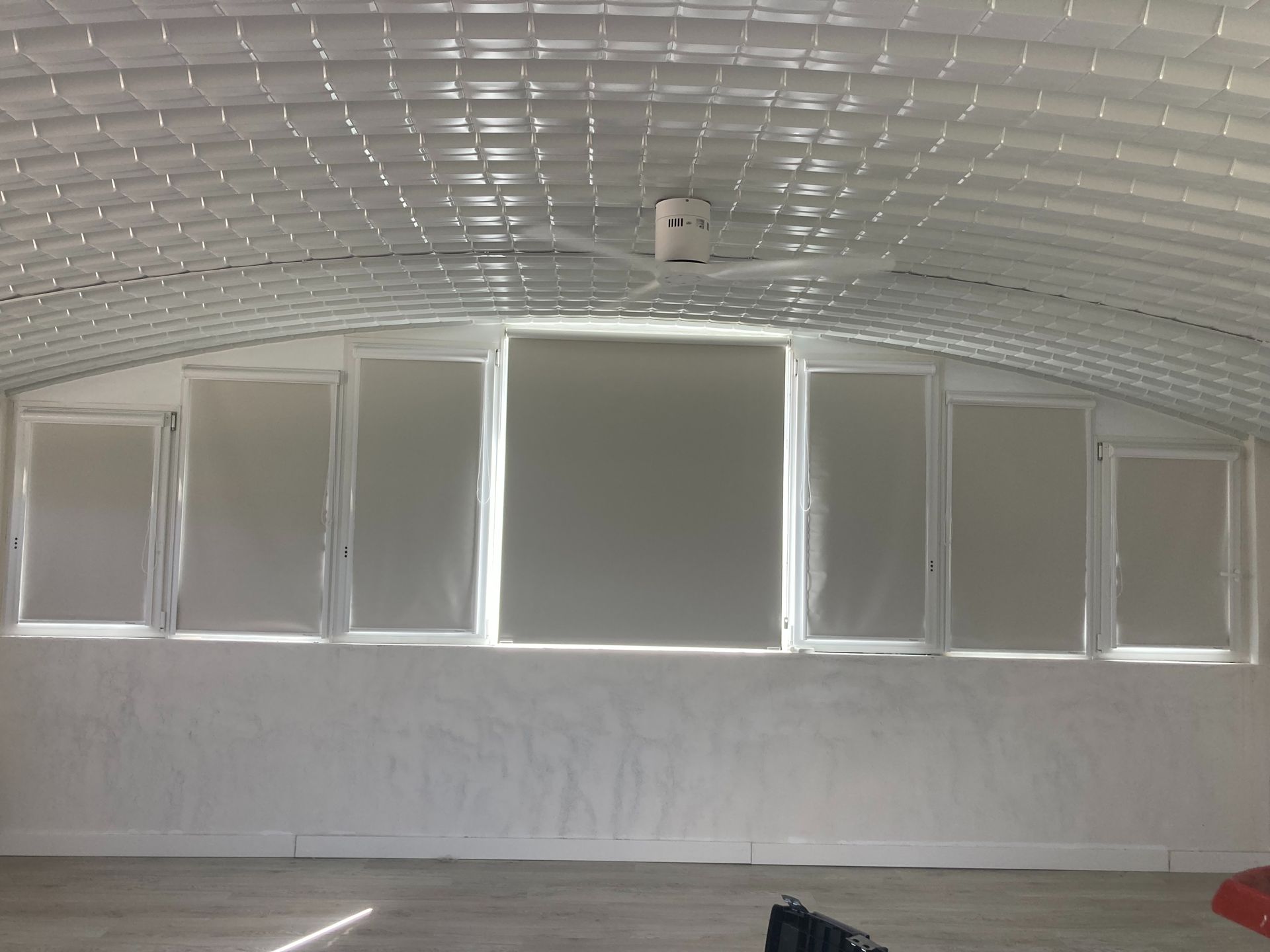 Una habitación con muchas ventanas y un ventilador de techo.