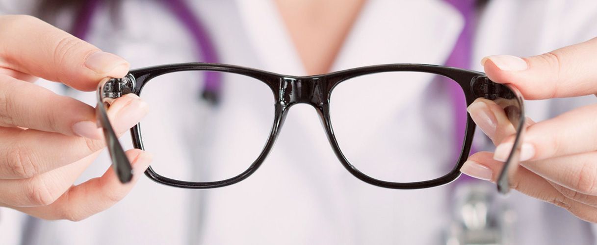Un médico sostiene un par de gafas en sus manos.