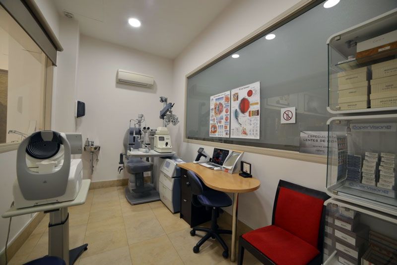 Una habitación con un escritorio y sillas y una ventana grande.