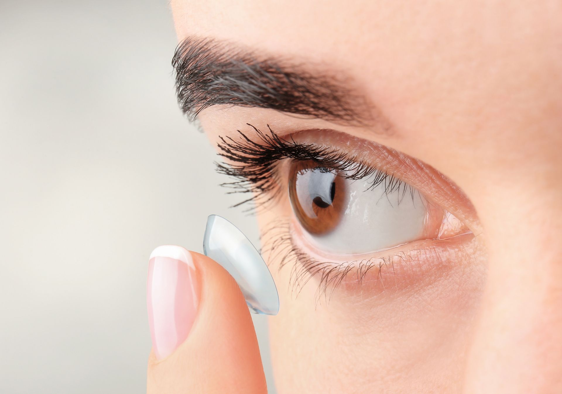 Eine Frau setzt eine Kontaktlinse in ihr Auge ein.