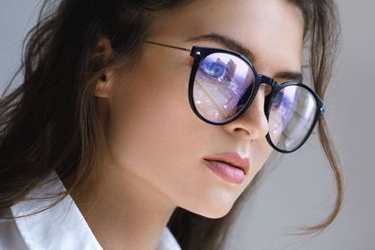 Eine Nahaufnahme einer Frau mit Sonnenbrille und weißem Hemd.