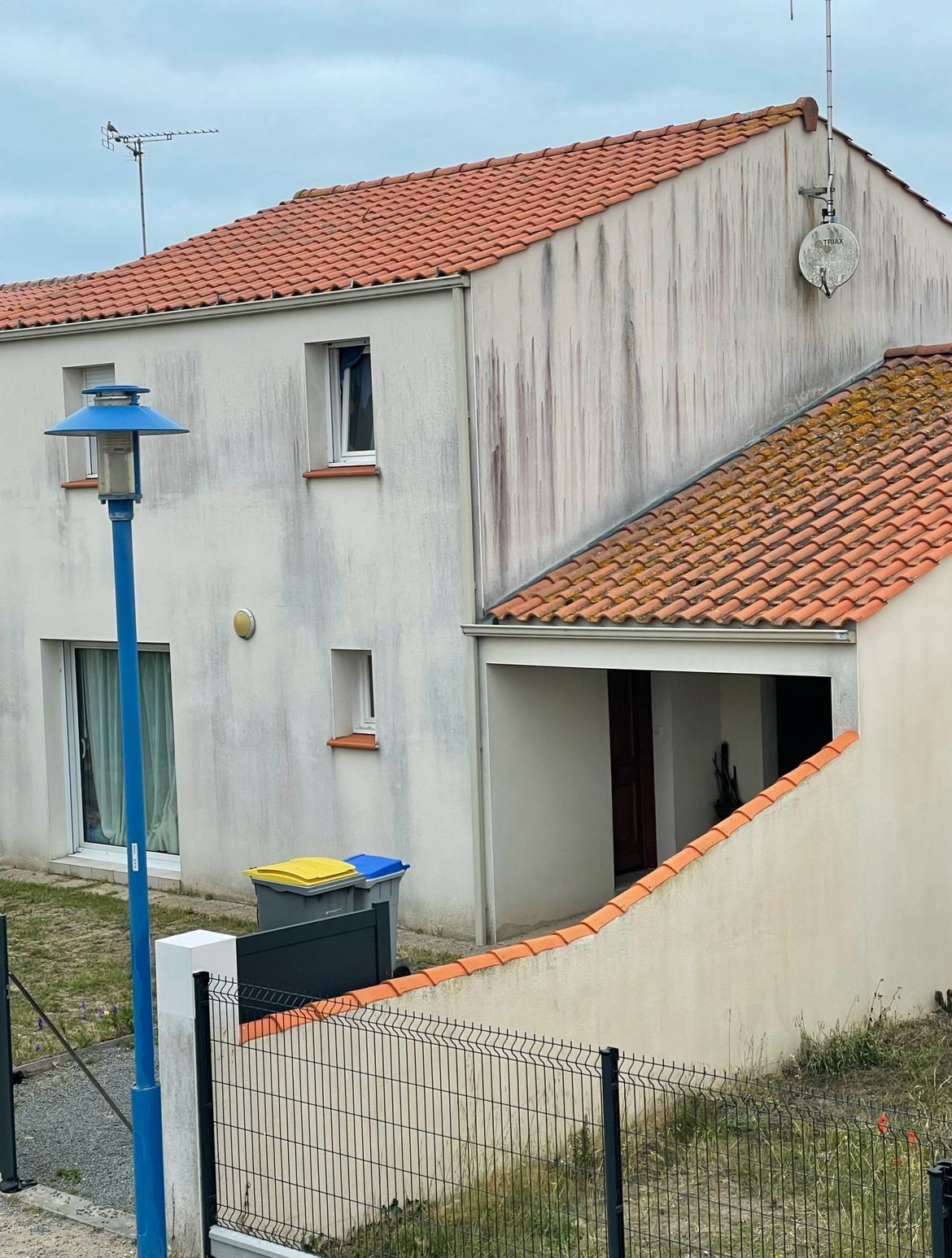 Maison dont la toiture est en cours de remplacement, avec échelle, benne à gravats et débris.