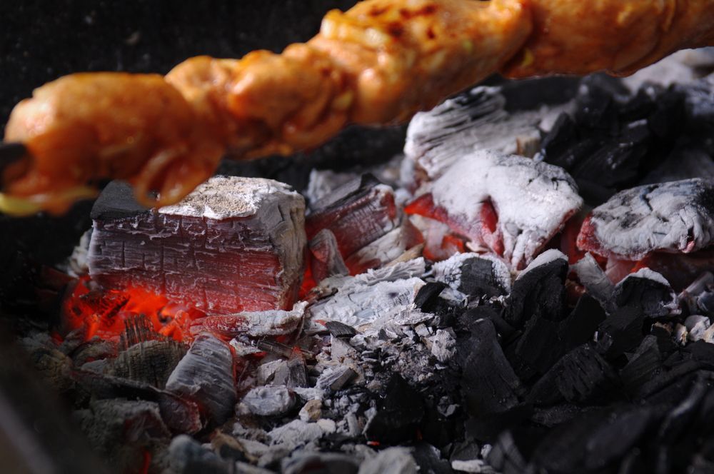 Se está cocinando una brocheta de pollo sobre una pila de carbón.