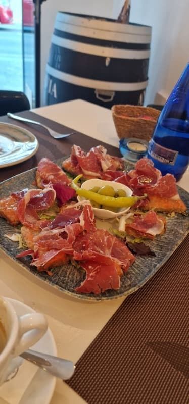 Un plato de comida está sobre una mesa al lado de una taza de café.