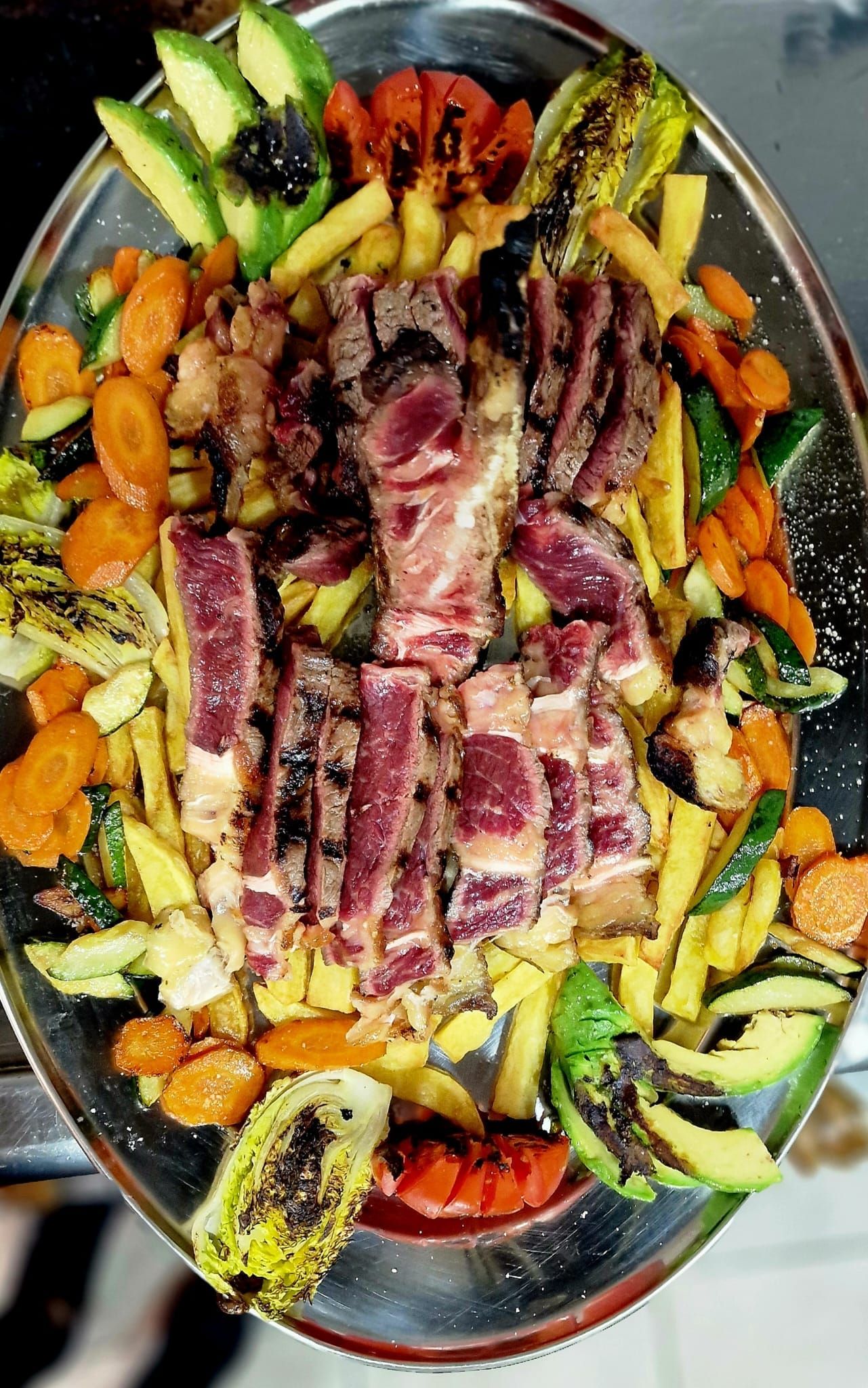 Un plato de carne y verduras sobre una mesa.
