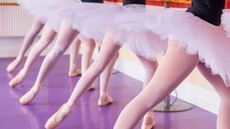 mehrere kleine Mädchen in Tutus neben einem Spiegel beim Balletttraining