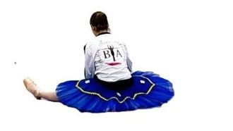 Beine mehrerer Balletttänzerinnen neben einer Ballettstange sind zu sehen