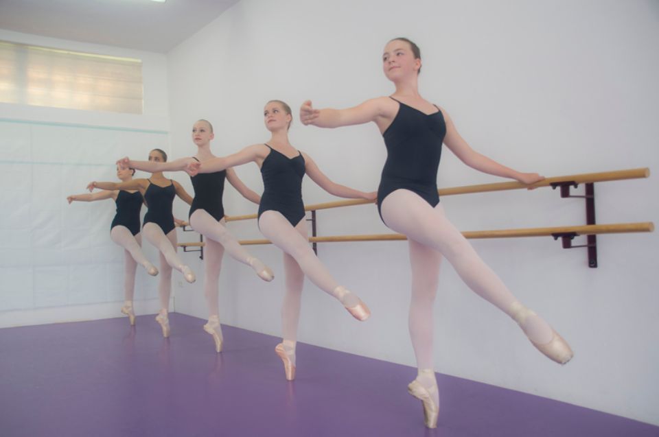 mehrere Tänzerinnen trainieren an der Ballettstange