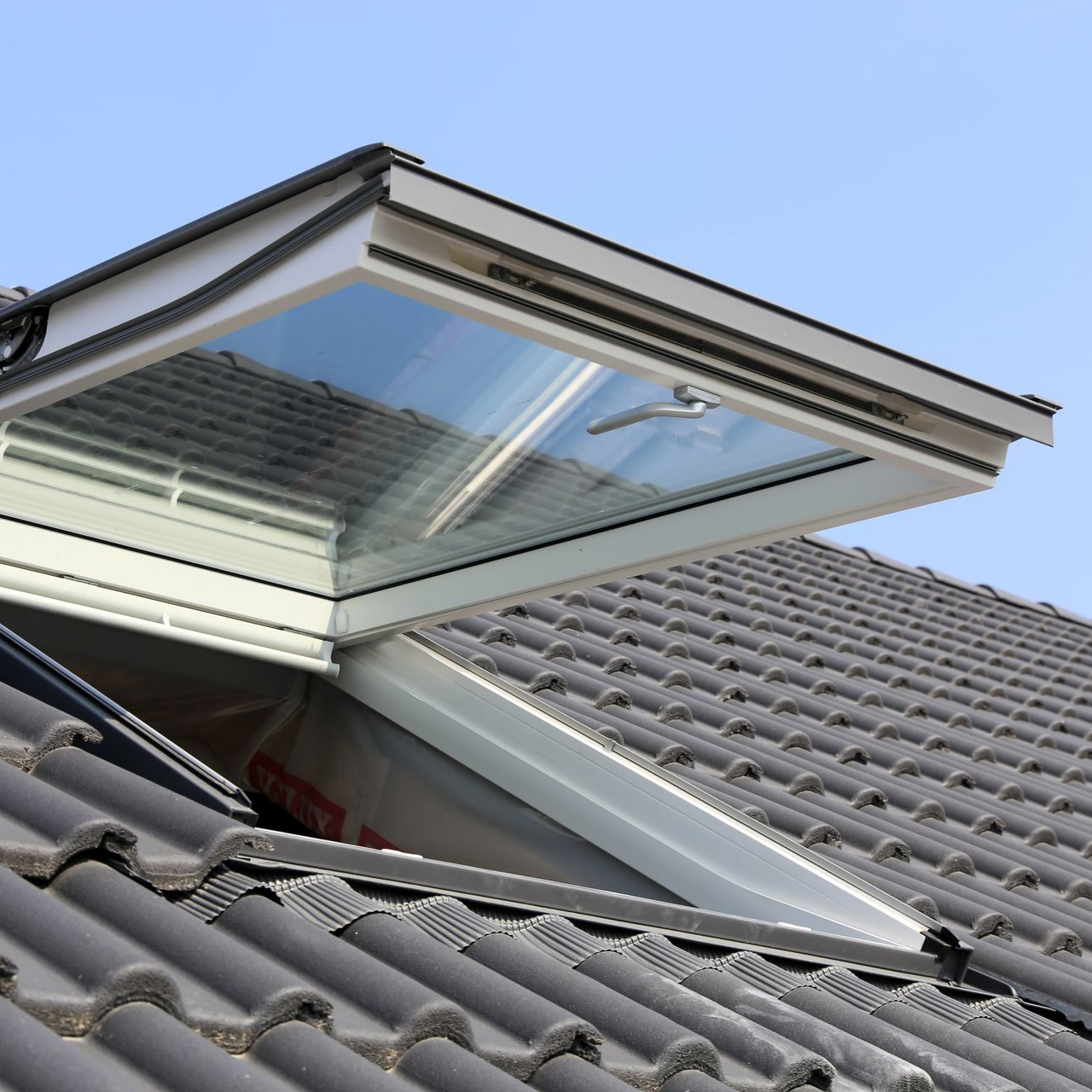 Fenêtre de toit ouverte sur une toiture en tuiles
