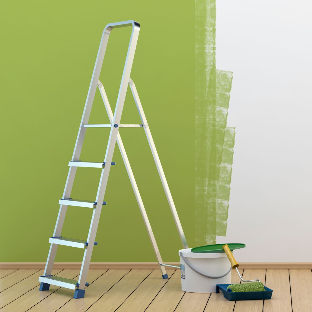 Pot de peinture vert et échelle contre un mur