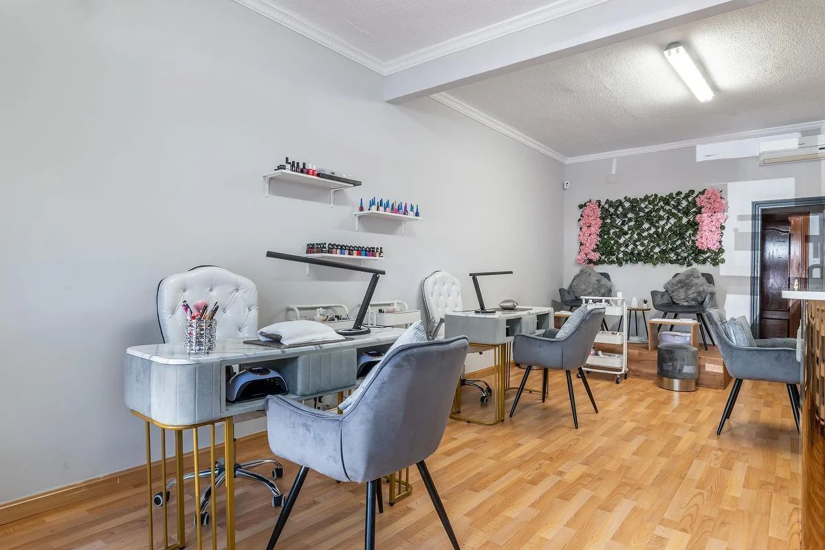 Oficina moderna en casa con escritorios, sillas, computadoras portátiles, estantes y piso de madera en una habitación luminosa.