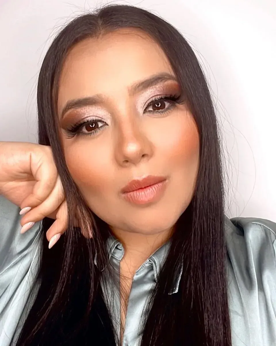 Una persona que lleva guantes médicos azules aplica esmalte de uñas de color morado oscuro en una uña del pie.