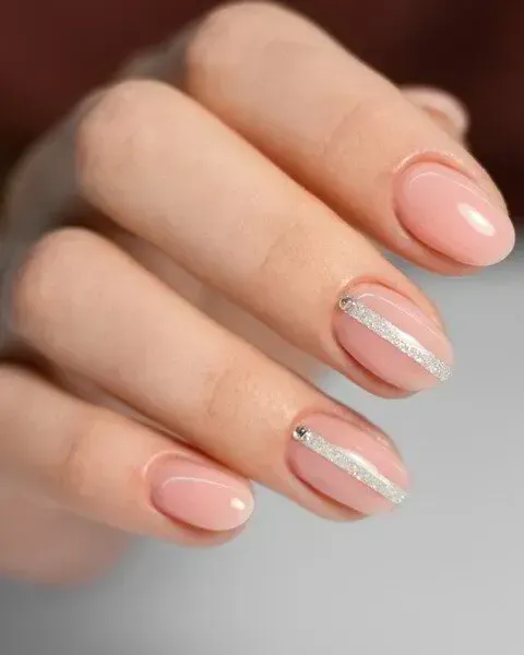 Una mano que muestra una manicura con esmalte rosa nude