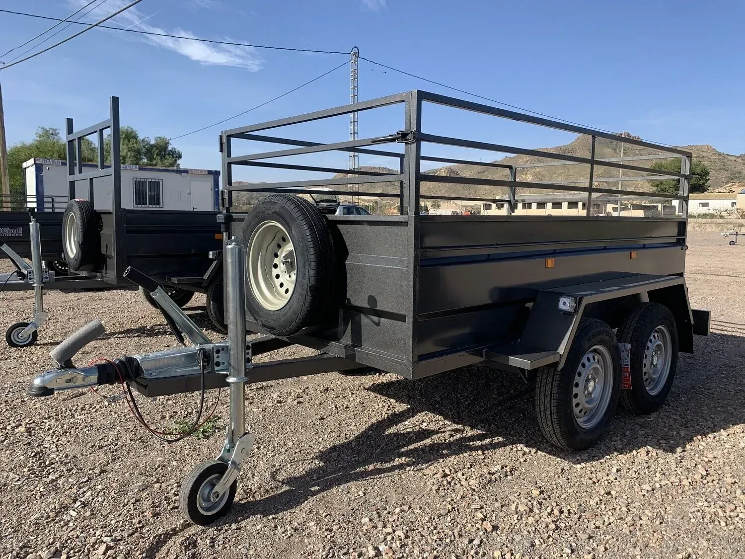 Un remolque con una valla encima está estacionado en un lote de grava.