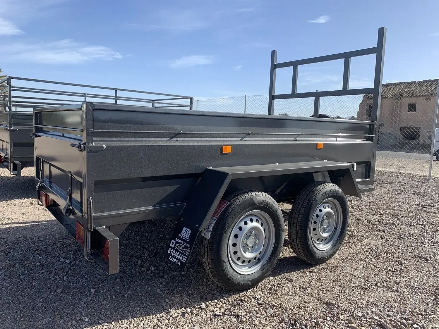 Un remolque negro está estacionado en un lote de grava.