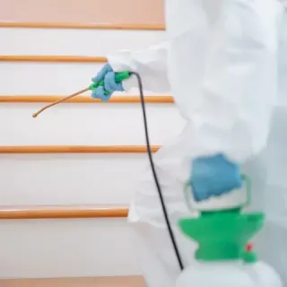 Una persona con un traje de protección está rociando una escalera con un pulverizador.