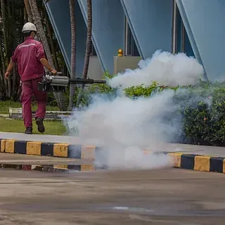 Un hombre está usando una máquina para rociar humo en una acera.