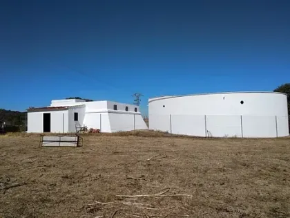Dos tanques blancos están sentados en un campo al lado de una casa.