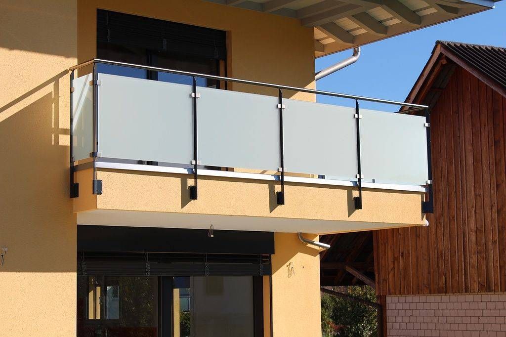 Ein Balkon mit einem Glasgeländer an der Seite eines Hauses