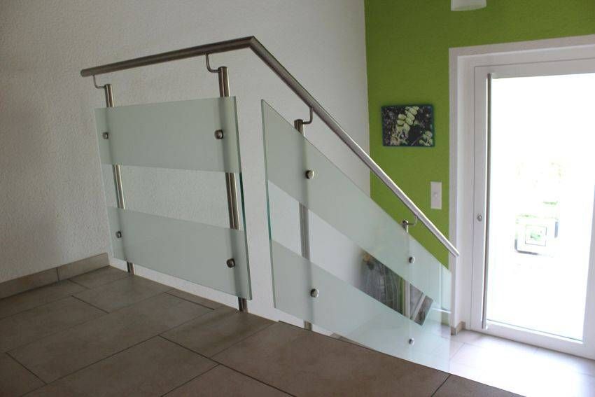 Eine Treppe mit Glasgeländer und grüner Wand