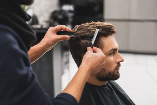 Homme qui se fait couper les cheveux par une paire de mains.