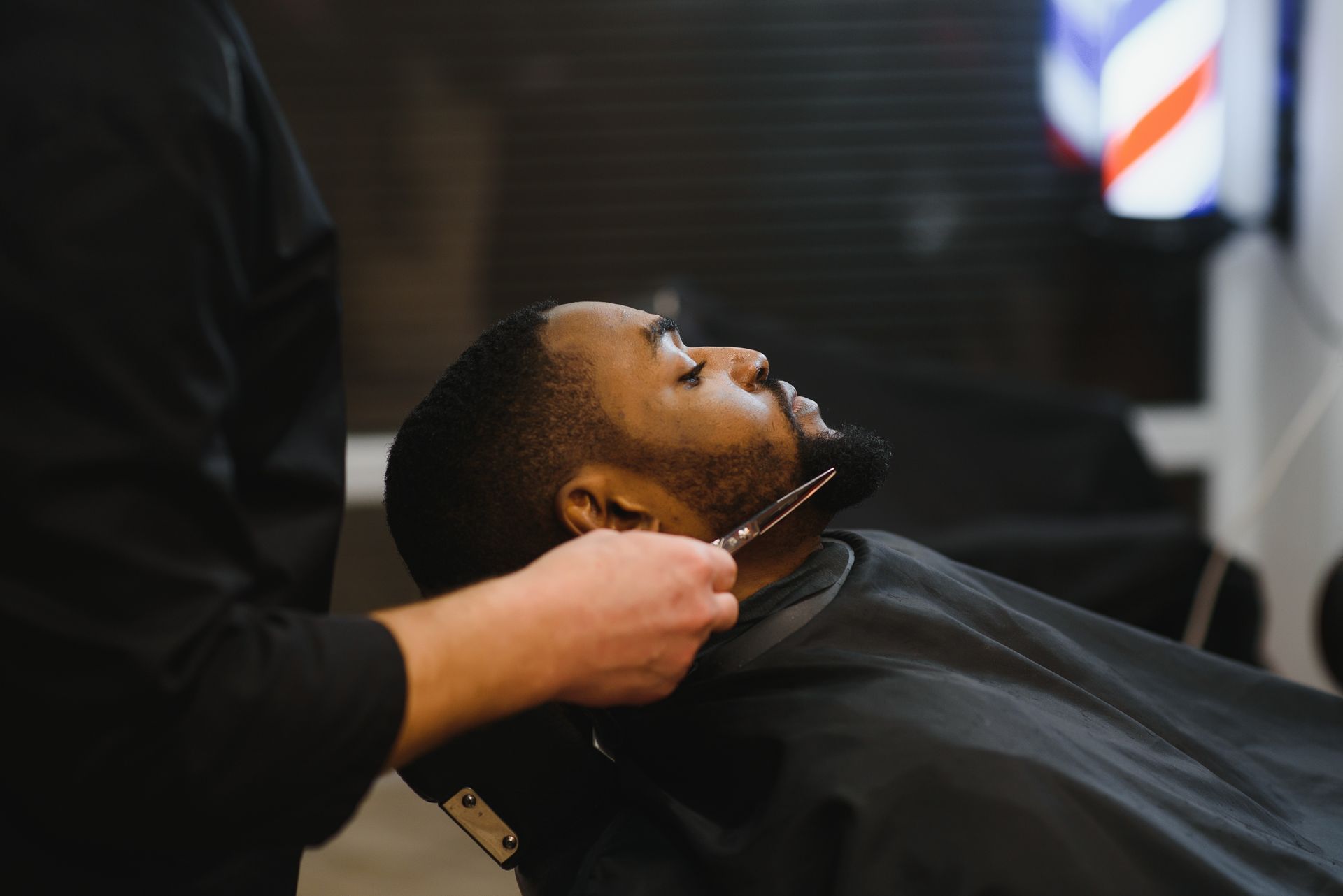 Coupe de barbe avec une personne allongée et une main tenant un rasoir.