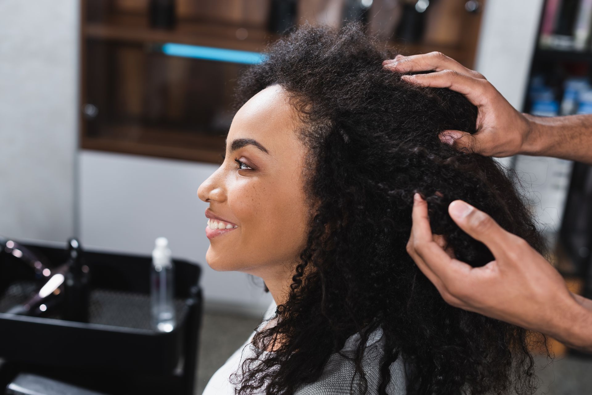 Personne avec des cheveux frisés, des mains les touchant.