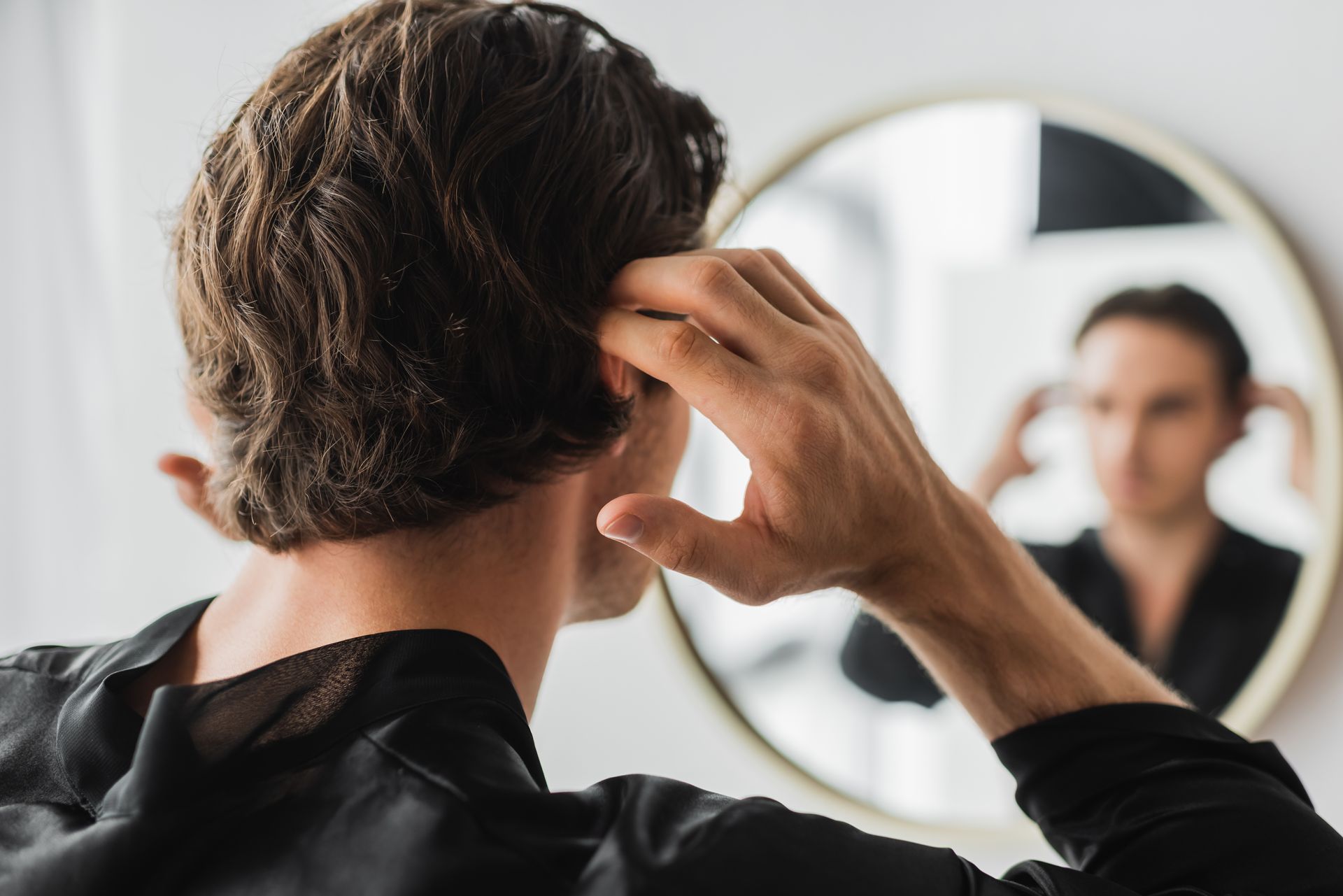 Homme devant un miroir, les mains à hauteur de tête.