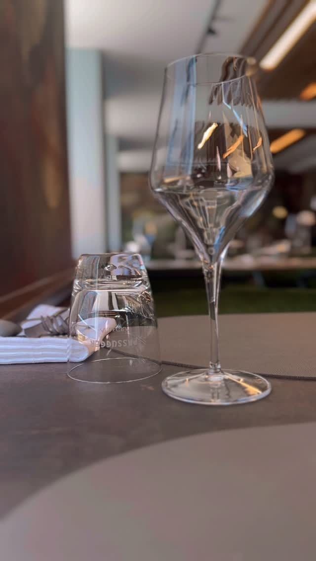 Auf einem Tisch in einem Restaurant stehen ein Weinglas und ein kleines Wasserglas.